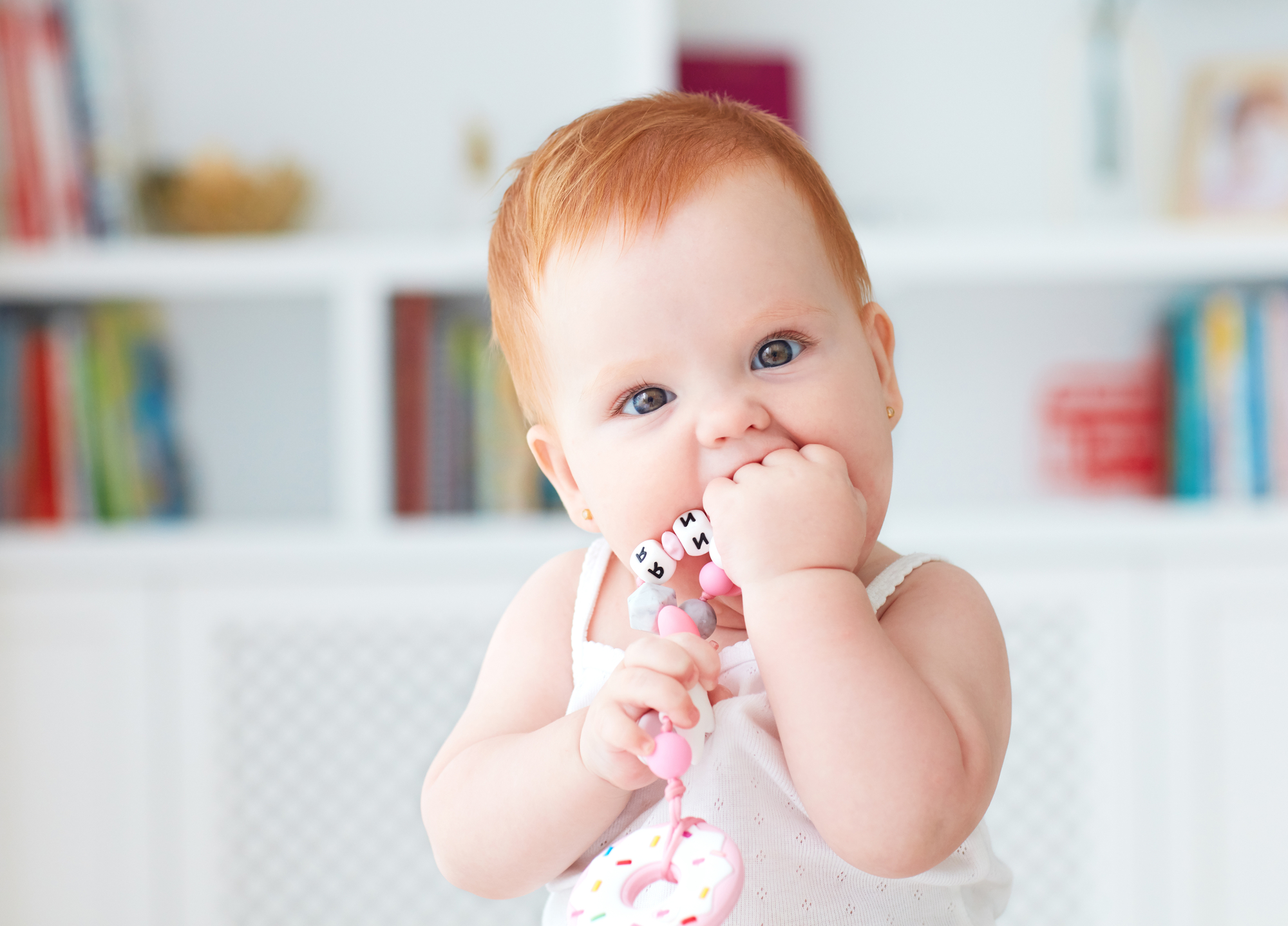 A baby is holding a toothbrush in her mouth.