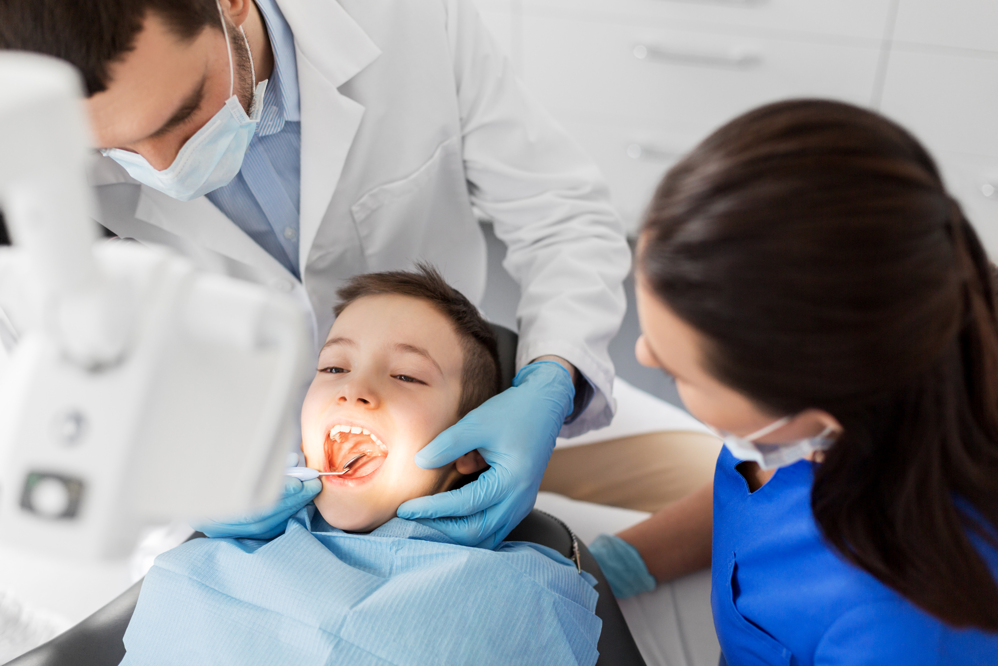 A young boy is being examined by a dentist.