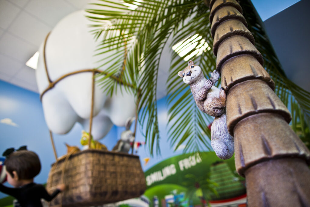 Smiling Seal Treatment Room 7squirrel A stuffed animal sitting on a palm tree in a room with a hot air balloon.
