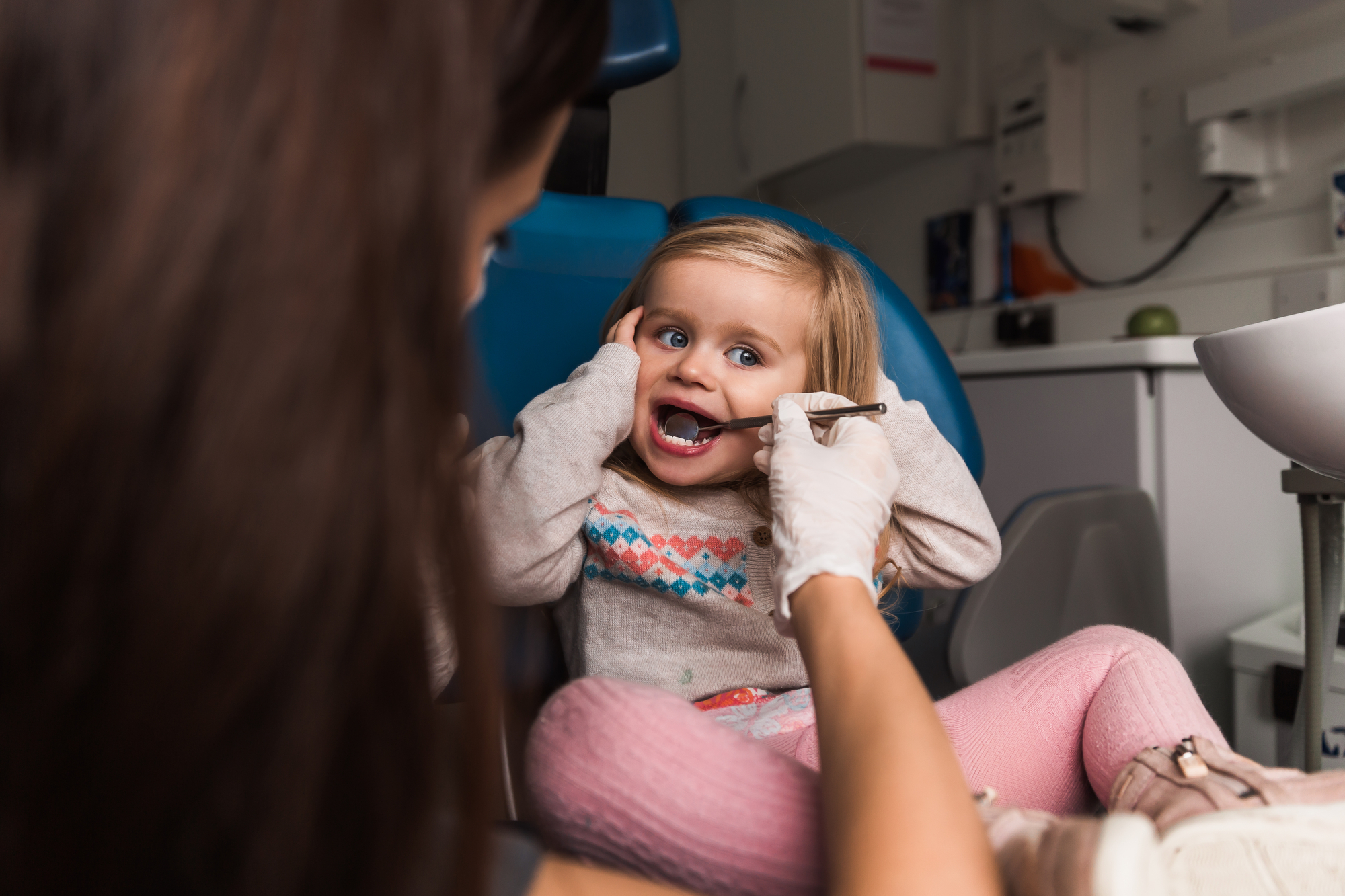 A little girl is getting her teeth cleaned by a dentist.